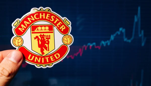 1 Eylül 2021 Manchester, İngiltere. Manchester United F.C. Futbol kulübü amblemi hisse senedi tablosunun arka planına karşı.