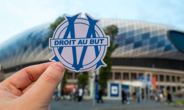 12 Eylül 2021, Marsilya, Fransa. Futbol kulübü Olympique de Marsilya 'nın amblemi modern stadyumun arka planına karşıdır..