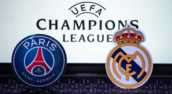 2 Ocak 2022 St. Petersburg, Rusya. UEFA Şampiyonlar Ligi 'nin 1 / 8 finallerinin futbol kulüplerinin amblemleri Paris Saint-Germain F.C. ve Real Madrid CF turnuva ambleminin arka planında.