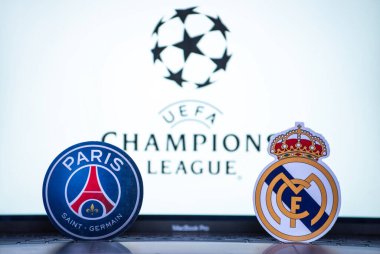 2 Ocak 2022 St. Petersburg, Rusya. UEFA Şampiyonlar Ligi 'nin 1 / 8 finallerinin futbol kulüplerinin amblemleri Paris Saint-Germain F.C. ve Real Madrid CF turnuva ambleminin arka planında.