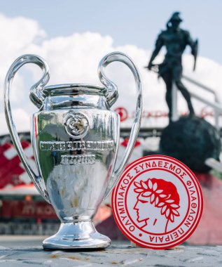 14 Haziran 2021 Atina, Yunanistan. Futbol kulübü Olympiacos Pire ve UEFA Şampiyonlar Ligi Kupası 'nın amblemi modern stadyumun arka planına karşıdır..