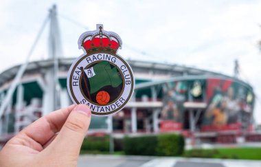 30 Ağustos 2021, Santander, İspanya. Racing de Santander futbol kulübünün amblemi modern bir stadyumun arka planına karşı..