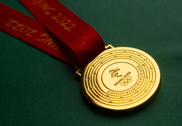 6 Ocak 2021, Pekin Çin. Yeşil zemin üzerinde 14. Olimpiyat Kış Oyunları 'nın altın madalyası.