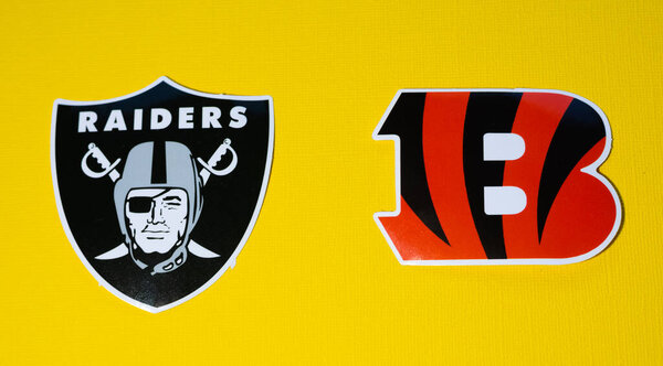 January 14, 2022 Cincinnati, Ohio. The emblems of the football clubs of the playoffs of the National Football League season 2021/2022 Cincinnati Bengals and Las Vegas Raiders on a yellow background.
