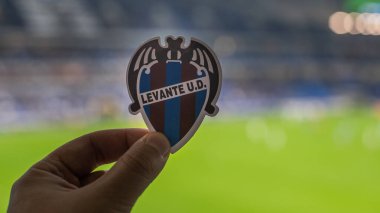 12 Eylül 2021, Valencia, İspanya. Futbol kulübü Levante UD 'nin amblemi modern bir stadyumun arka planına karşıdır..