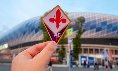 12 Eylül 2021, Floransa, İtalya. Futbol kulübü ACF Fiorentina 'nın amblemi modern stadyumun arka planına karşıdır..