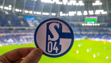 12 Eylül 2021, Gelsenkirchen, Almanya. Futbol kulübü FC Schalke 04 'ün amblemi modern stadyumun arka planına karşıdır..
