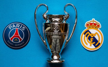 19 Aralık 2021 St. Petersburg, Rusya. UEFA Şampiyonlar Ligi 'nin 1 / 8 finallerinin futbol kulüplerinin amblemleri Paris Saint-Germain F.C. Real Madrid CF ve mavi arka planda bir fincan..