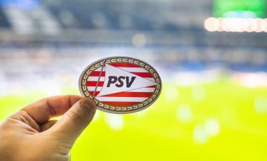 12 Eylül 2021, Eindhoven, Hollanda. PSV Eindhoven futbol kulübünün amblemi modern bir stadyumun arka planına karşıdır..