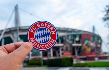 30 Ağustos 2021, Münih, Almanya. Futbol kulübü FC Bayern Münih 'in amblemi modern bir stadyumun arka planında.