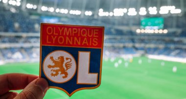 12 Eylül 2021, Lyon, Fransa. Futbol kulübü Olympique Lyonnais 'in amblemi modern stadyumun arka planına karşıdır..