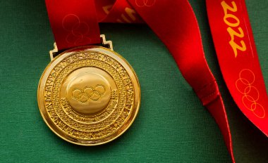 27 Ocak 2022, Pekin, Çin. Yeşil arka planda 14. Olimpiyat Kış Oyunları altın madalyası.
