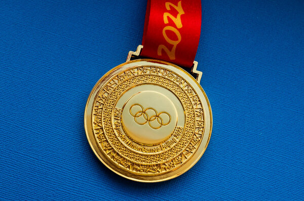 January 27, 2022, Beijing, China. XXIV Olympic Winter Games gold medal on a blue background.