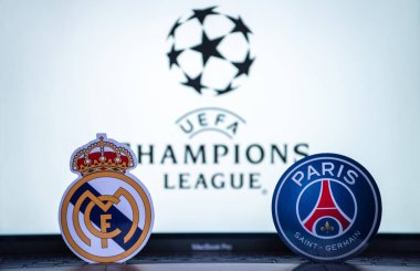 2 Ocak 2022 St. Petersburg, Rusya. UEFA Şampiyonlar Ligi 'nin 1 / 8 finallerinin futbol kulüplerinin amblemleri Paris Saint-Germain F.C. ve Real Madrid CF turnuva ambleminin arka planında.