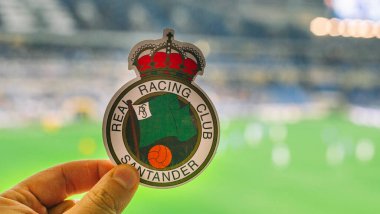 12 Eylül 2021, Santander, İspanya. Racing de Santander futbol kulübünün amblemi modern bir stadyumun arka planına karşı..