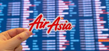 11 Aralık 2021, Kuala Lumpur, Malezya. AirAsia havayollarının amblemi, uluslararası havaalanındaki uçuş çizelgeleriyle birlikte elektronik bir skorbordun arka planına karşı..
