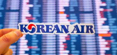 11 Aralık 2021, Seul, Güney Kore. Kore Havayolları amblemi, uluslararası bir havaalanındaki uçuş çizelgesi olan elektronik bir panonun arka planına karşı..