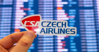 11 Aralık 2021, Prag, Çek Cumhuriyeti. Çek Hava Yolları 'nın amblemi, uluslararası havaalanındaki uçuş çizelgesine sahip elektronik bir panonun arka planına karşı..