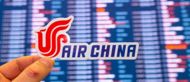 11 Aralık 2021, Pekin, Çin. Air China havayollarının amblemi, uluslararası bir havaalanındaki uçuş çizelgesine sahip elektronik bir panonun arka planına karşı..