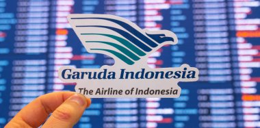 11 Aralık 2021, Tangerang, Endonezya. Garuda Endonezya Havayolları 'nın amblemi, uluslararası havaalanının uçuş çizelgesine sahip elektronik bir panonun arka planına karşı..
