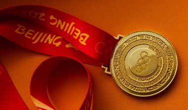 27 Ocak 2022, Pekin, Çin. Turuncu arka planda 14. Olimpiyat Kış Oyunları altın madalyası.