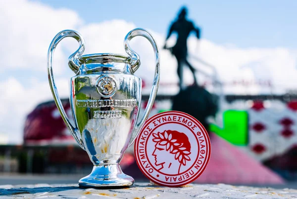 14 Haziran 2021 Atina, Yunanistan. Futbol kulübü Olympiacos Pire ve UEFA Şampiyonlar Ligi Kupası 'nın amblemi modern stadyumun arka planına karşıdır..