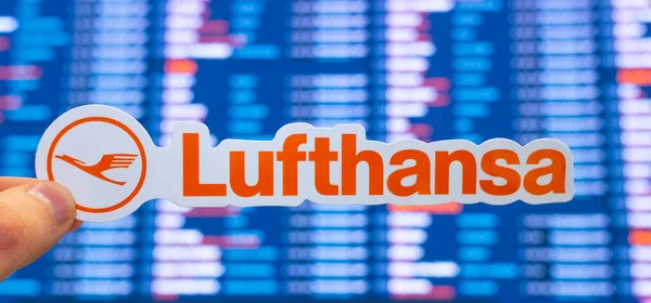 11 Aralık 2021, Münih, Almanya. Lufthansa amblemi, uluslararası havaalanındaki uçuş çizelgeleriyle elektronik bir panonun arka planına karşı..
