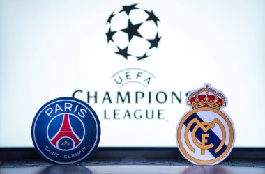 2 Ocak 2022 St. Petersburg, Rusya. UEFA Şampiyonlar Ligi 'nin 1 / 8 finallerinin futbol kulüplerinin amblemleri Paris Saint-Germain F.C. ve Real Madrid CF turnuva ambleminin arka planında.