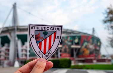 30 Ağustos 2021, Bilbao, İspanya. Atletik Bilbao futbol kulübünün amblemi ve UEFA Şampiyonlar Ligi Kupası modern bir stadyumun arka planına karşı..