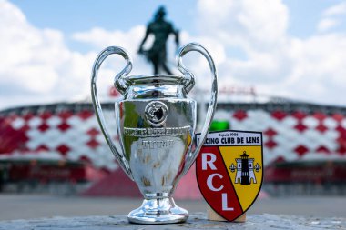14 Haziran 2021, Lens, Fransa. RC Lens futbol kulübü ve UEFA Şampiyonlar Ligi Kupası 'nın amblemi modern bir stadyumun arka planına karşıdır..