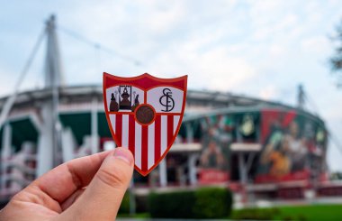 30 Ağustos 2021, Sevilla, İspanya. Futbol kulübü Sevilla FC 'nin amblemi modern bir stadyumun arka planına karşıdır..