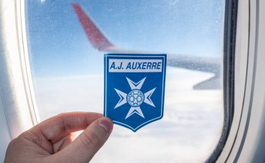 6 Aralık 2021. Auxerre, Fransa. Bir uçak penceresinin arkasındaki AJ Auxerre futbol kulübünün amblemi..
