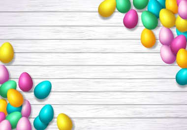 Ahşap zemin üzerine yayılmış parlak renkli yumurtalarla Paskalya çerçevesi