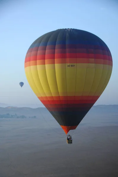 Hot Air Balloon floating over the desert sand