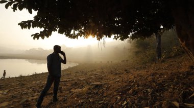 Telefonu olan bir adam silueti.