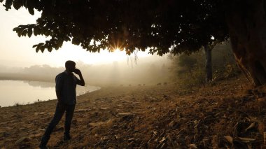 Telefonu olan bir adam silueti.