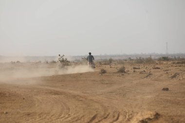 Tozlu yolda koşan bir adamın arka görüntüsü