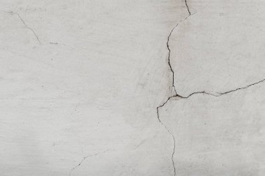 Grunge beton duvarı çatlattı. Beyaz alçılı eski bir duvar ve siyah-beyaz tonda çatlak kabuk soyma alanı. Pis geniş tuğla duvar.