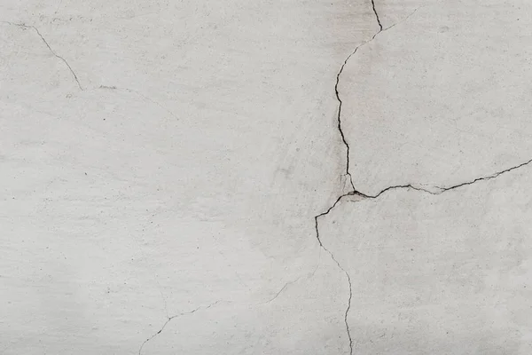 Grunge beton duvarı çatlattı. Beyaz alçılı eski bir duvar ve siyah-beyaz tonda çatlak kabuk soyma alanı. Pis geniş tuğla duvar.