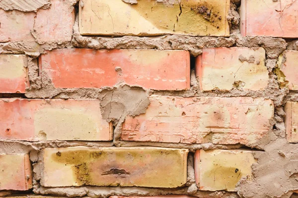 Old brick wall background, texture, structure. Old broken brick, cement joints, closeup. Crumbling from old age. Construction and repair. Concept of devastation, decline. Rustic style