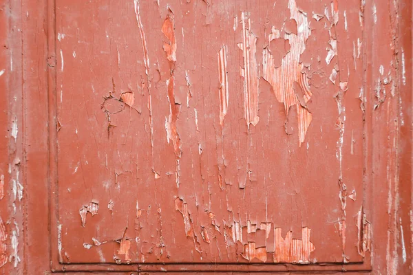 Grunge red painted wooden textured background. Old rustic door with peeling red paint closeup. Red paint peeled off from the old boards and the wood texture cracked. Vintage abstract grunge background