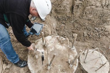 İnşaat işi. Beton yığını üzerinde sismik test. PIT Elle Tutulan Çekiç, PIT Hızölçer ve Yığın Bükülme Testi kullanarak kazıklardaki çıkıntıları ve boşlukları tespit eden mühendis.