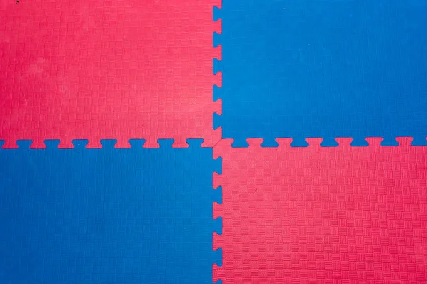 Eva foam rubber floor puzzle mats texture, colorful floor mat background. Multicolored soft elements. Blue and pink puzzles connected