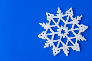 Mavi kağıtta tek bir kar tanesi. Kar taneli klasik Noel kartpostalı. Güzel noel yıldızları mavi arka planda