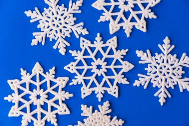 Mavi kağıt üzerinde beyaz kar taneleri süsü. Kar taneli klasik Noel kartpostalı. Güzel noel yıldızları mavi arka planda