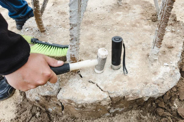 Construction works. Seismic test on concrete pile. Engineer using the PIT Hand-Held Hammer, the PIT Accelerometer and the Pile Integrity Tester to detect Neck Bulge and Void in the piles