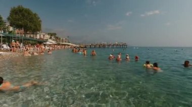 KEMER, TURKEY, 22, OCT.2021: Deniz sahilinde dinlenen insanların görüntüleri güneş şemsiyeleri altında güneşlenen ve kristal berrak suyla Akdeniz 'de yüzen insanların görüntüleri. Otel deniz kenarı.