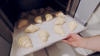 Baker, yalıtıcıdan çiğ kruvasan alıyor ve Combi vapurunda pişirmek için ayarlıyor. Yükselen hamur