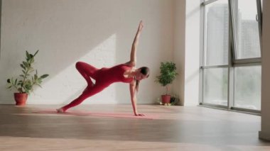 Kırmızı spor üniformalı genç bir kadın yoga stüdyosunda vasisthasana yapıyor. Sağlıklı yaşam tarzı kavramı