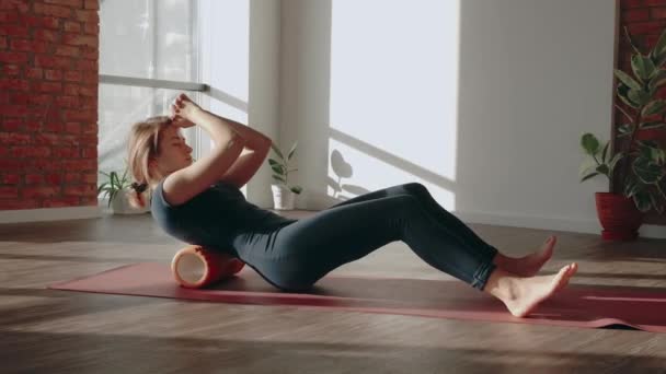 Entrenamiento de rodillo de espalda. Mujer haciendo estiramiento y masaje muscular con rodillo de espuma después del entrenamiento — Vídeo de stock